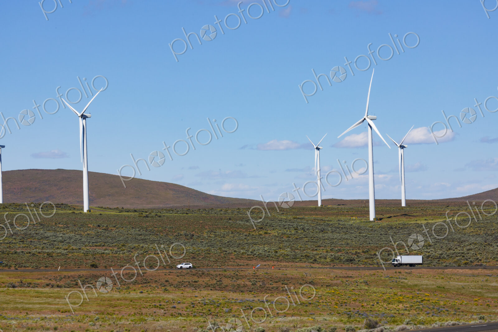 Wind turbines on the rolling hills of Kittikas county in Washington state, tall white…
