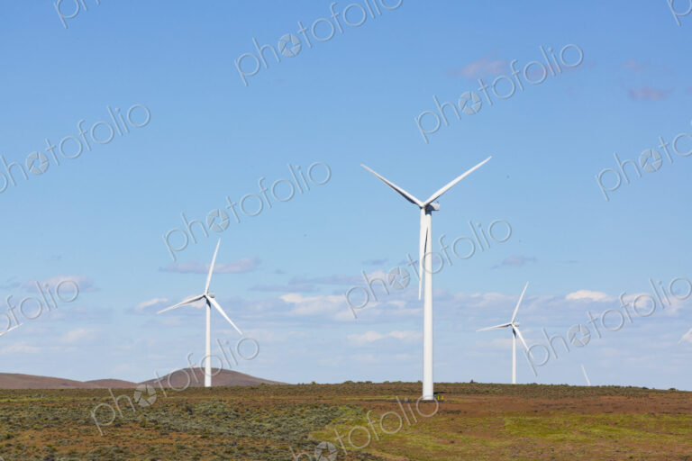 Wind turbines on the rolling hills of Kittikas county in Washington state, tall white…