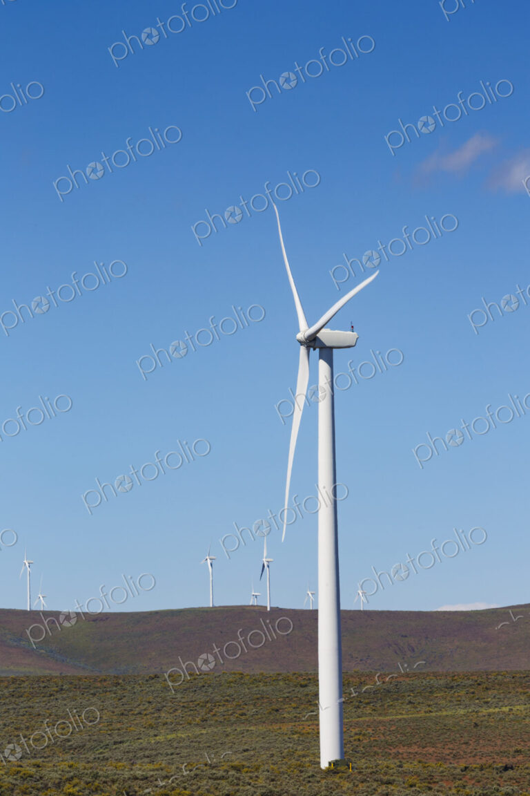 Wind turbines on the rolling hills of Kittikas county in Washington state, tall white…