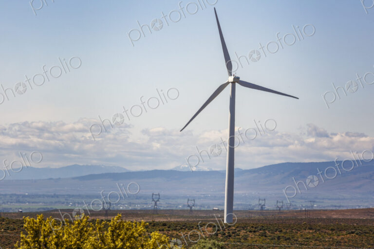 Wind turbines on the rolling hills of Kittikas county in Washington state, tall white…