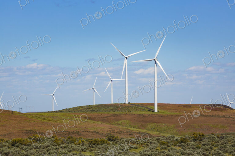 Wind turbines on the rolling hills of Kittikas county in Washington state, tall white…