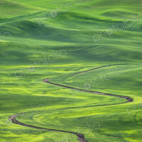 Winding irrigation ditch through rolling hills in rural landscape