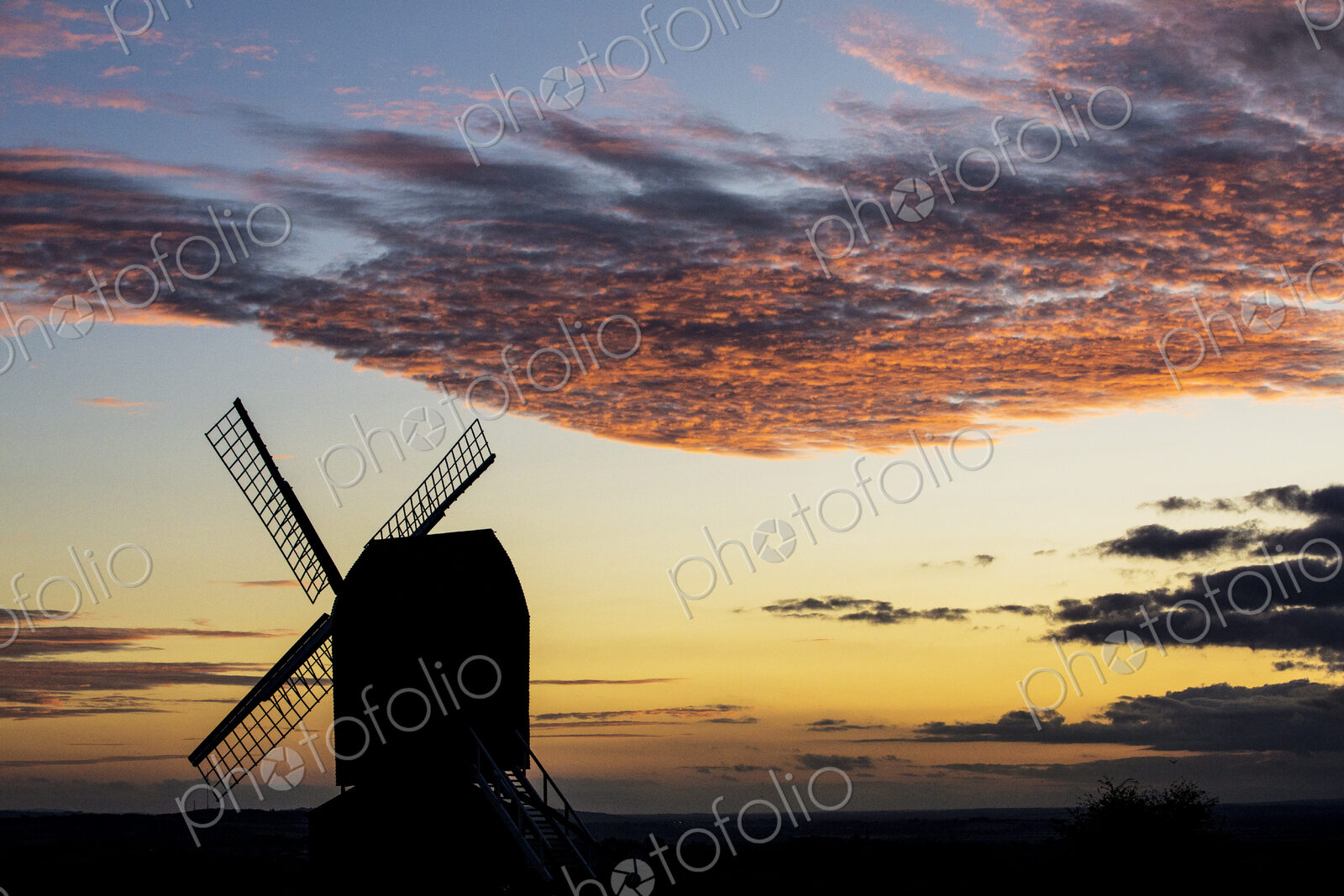 Windmill at sunset under a romantic cloudy sky.