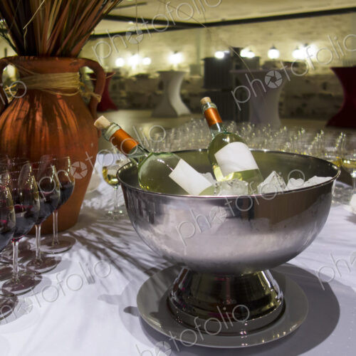 Wine bottles in metal ice bucket. Cooler with ice cubes. Wine glasses.