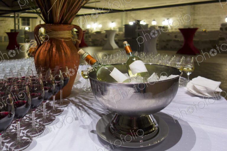Wine bottles in metal ice bucket. Cooler with ice cubes. Wine glasses.