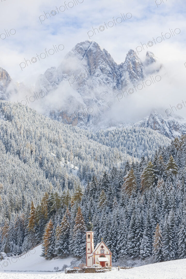 Winter landscape with church, forest and snow-capped mountains.