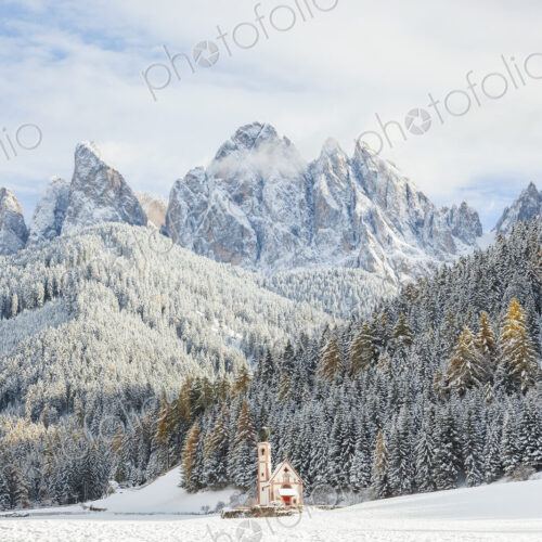 Winter landscape with church, forest and snow-capped mountains.