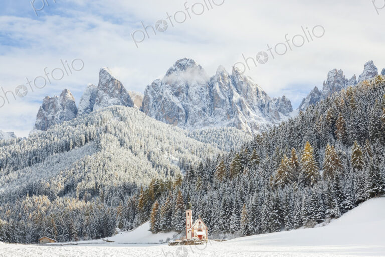 Winter landscape with church, forest and snow-capped mountains.