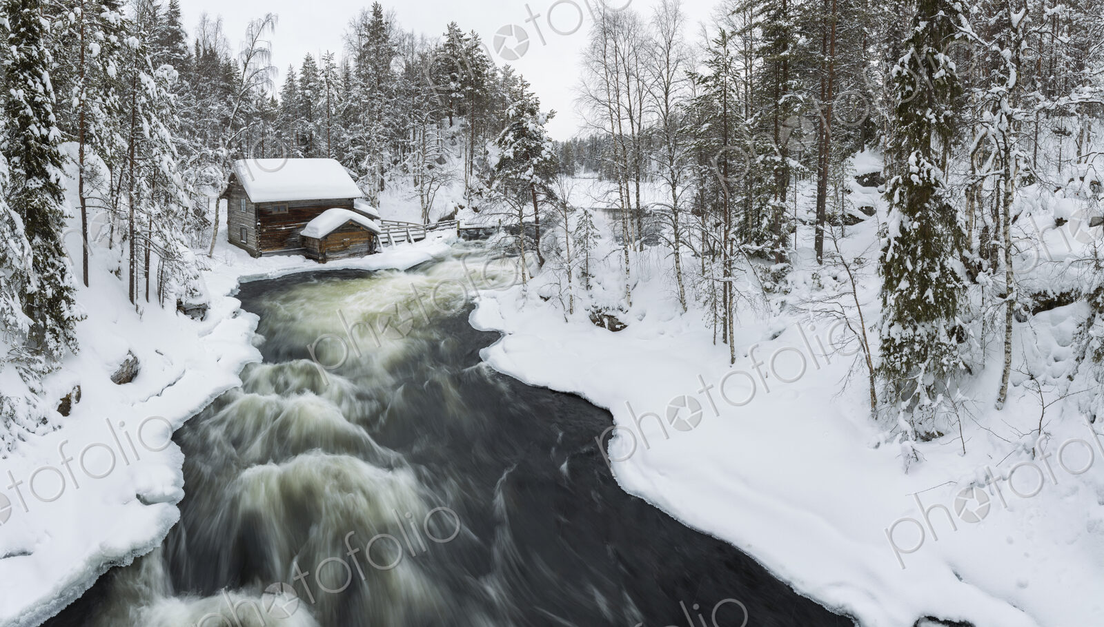 Winter landscape with log cabin and rapid in forest with snow-covered trees.