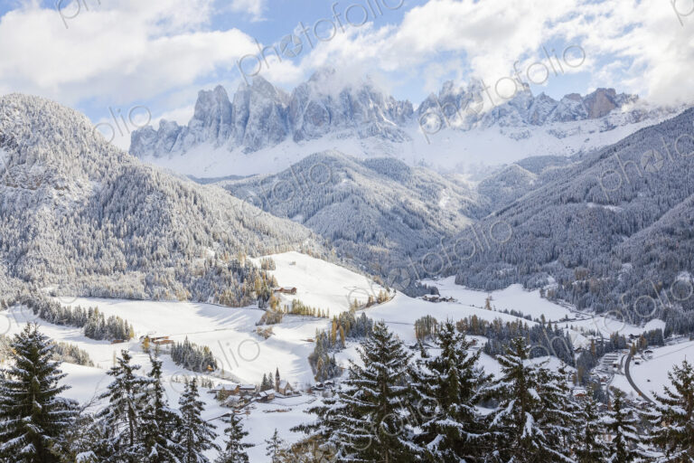 Winter landscape with valley, forest and snow-capped mountains.