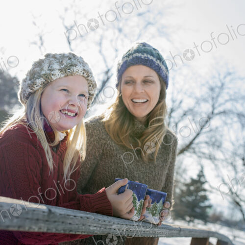 Winter scenery with snow on the ground. A child and an adult having a hot drink on a… Winter scenery with snow on the ground. A child and an adult having a hot drink on a…
