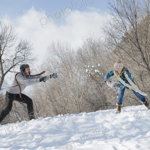Winter scenery with snow on the ground. A couple having a snowball fight.