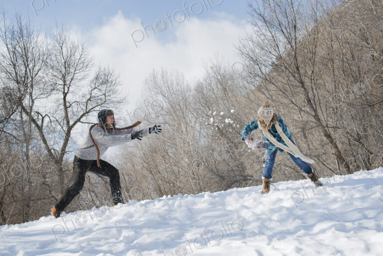 Winter scenery with snow on the ground. A couple having a snowball fight.