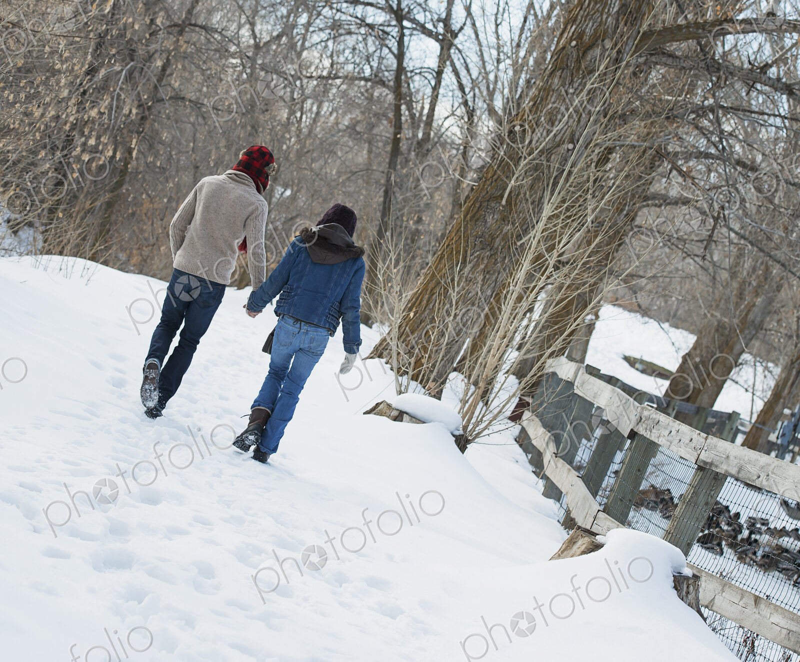 Winter scenery with snow on the ground. A couple walking hand in hand along a path.