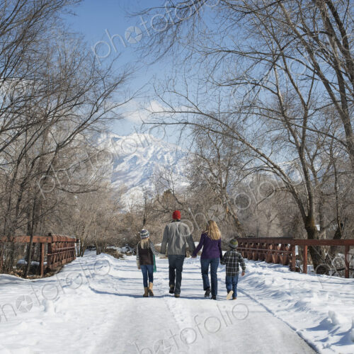 Winter scenery with snow on the ground. A family, adults and two children, walking… Winter scenery with snow on the ground. A family, adults and two children, walking…