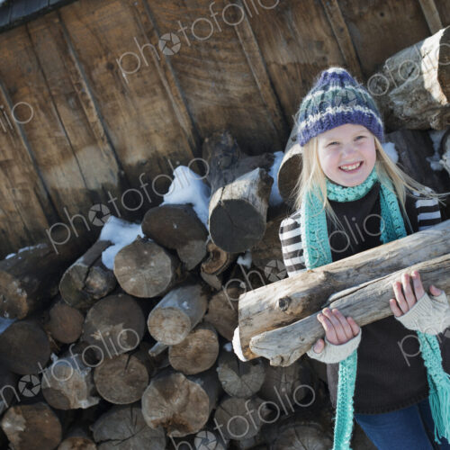 Winter scenery with snow on the ground. A girl collecting firewood from the log pile. Winter scenery with snow on the ground. A girl collecting firewood from the log pile.