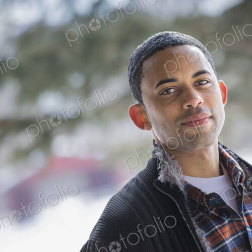 Winter scenery with snow on the ground. A man wearing a checked shirt and open jacket.