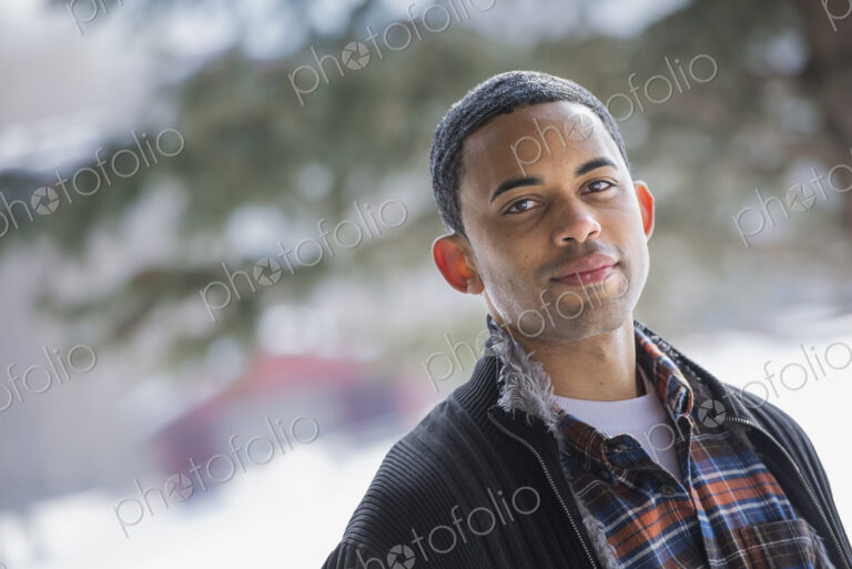 Winter scenery with snow on the ground. A man wearing a checked shirt and open jacket.