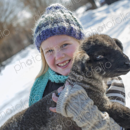 Winter scenery with snow on the ground. A young girl holding a young lamb. Winter scenery with snow on the ground. A young girl holding a young lamb.