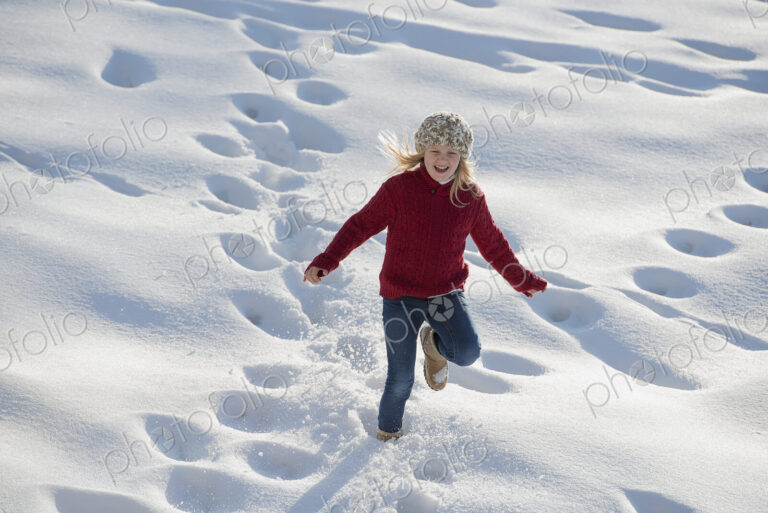 Winter scenery with snow on the ground. A young girl running through deep snow making…