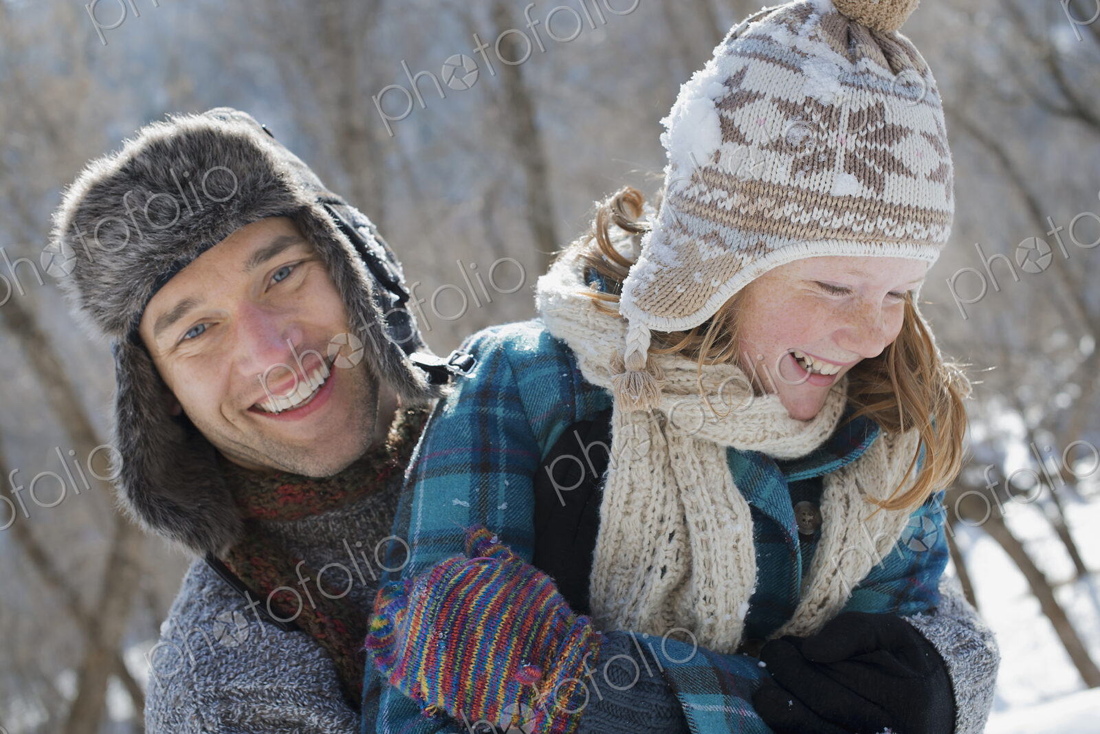 Winter scenery with snow on the ground. A young girl with a bobble hat and scarf and a…