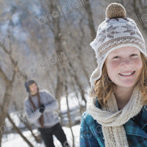 Winter scenery with snow on the ground. A young girl with a bobble hat and scarf…