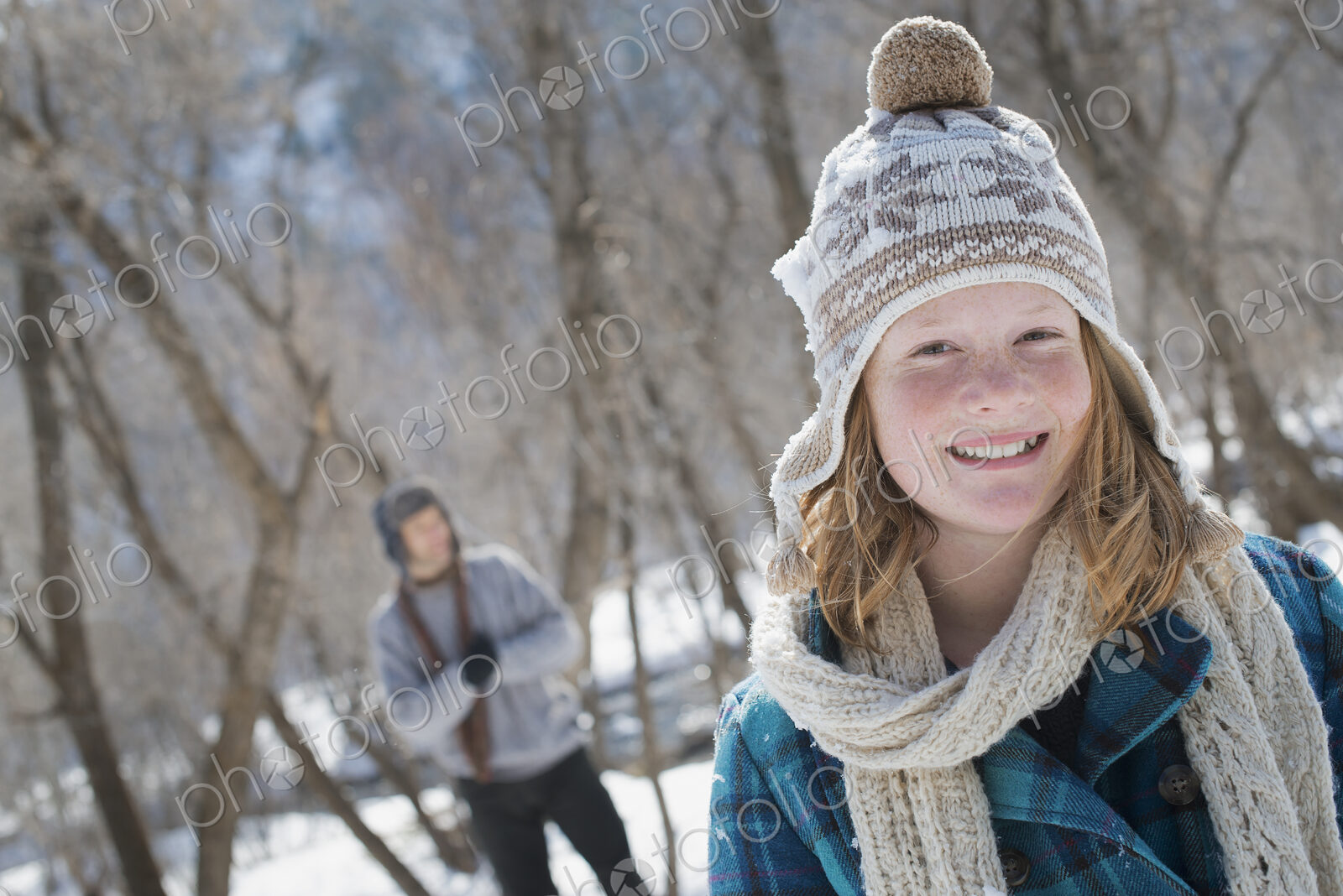 Winter scenery with snow on the ground. A young girl with a bobble hat and scarf…