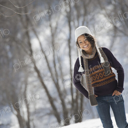 Winter scenery with snow on the ground. A young woman wearing a woolley hat.