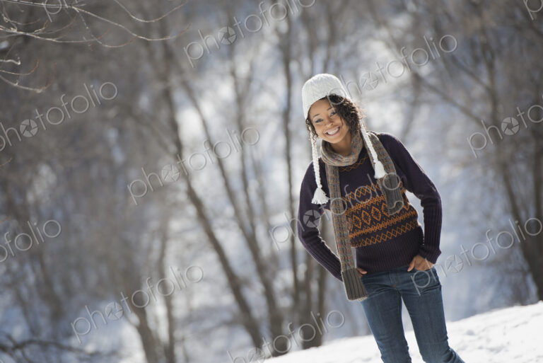 Winter scenery with snow on the ground. A young woman wearing a woolley hat.
