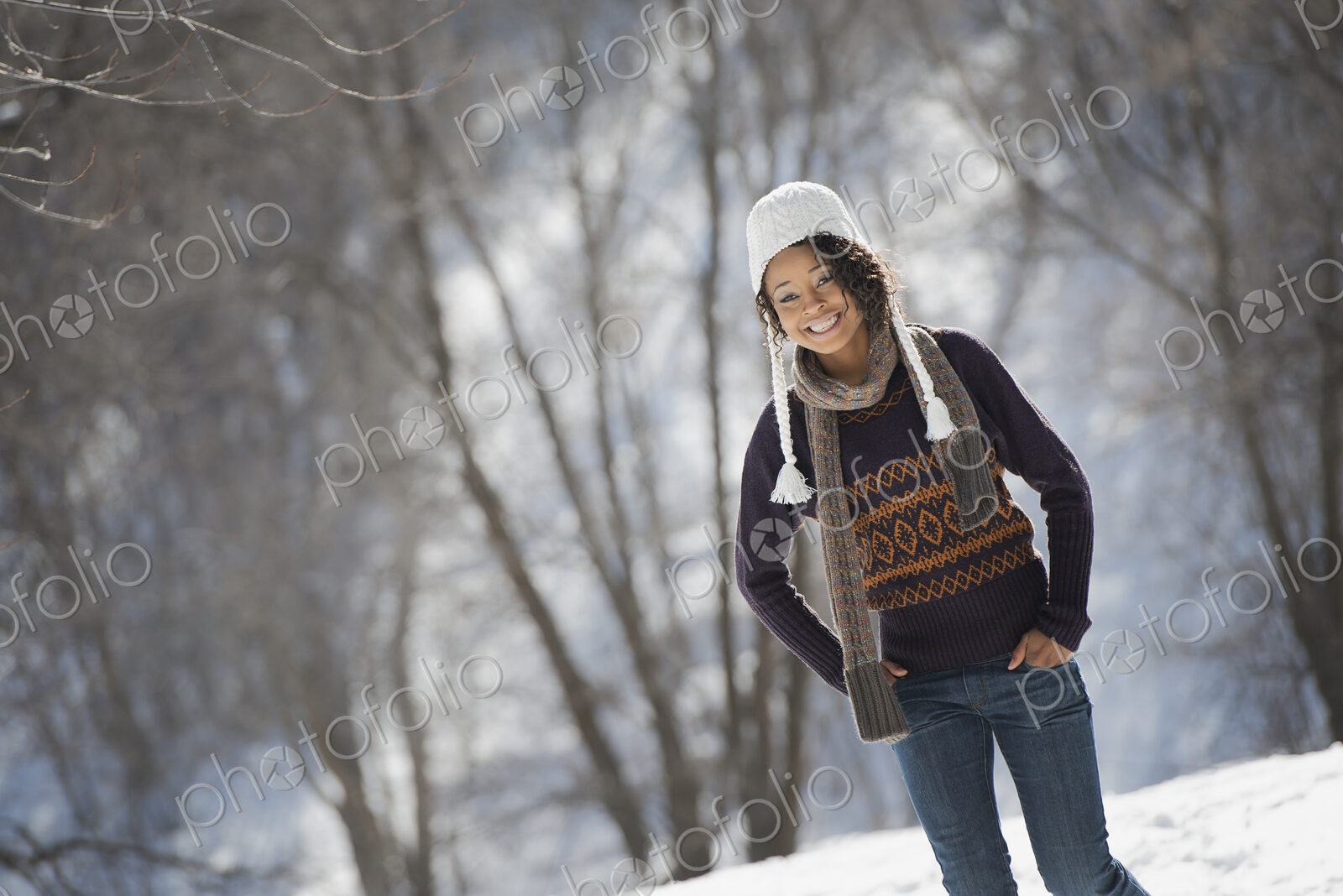 Winter scenery with snow on the ground. A young woman wearing a woolley hat.