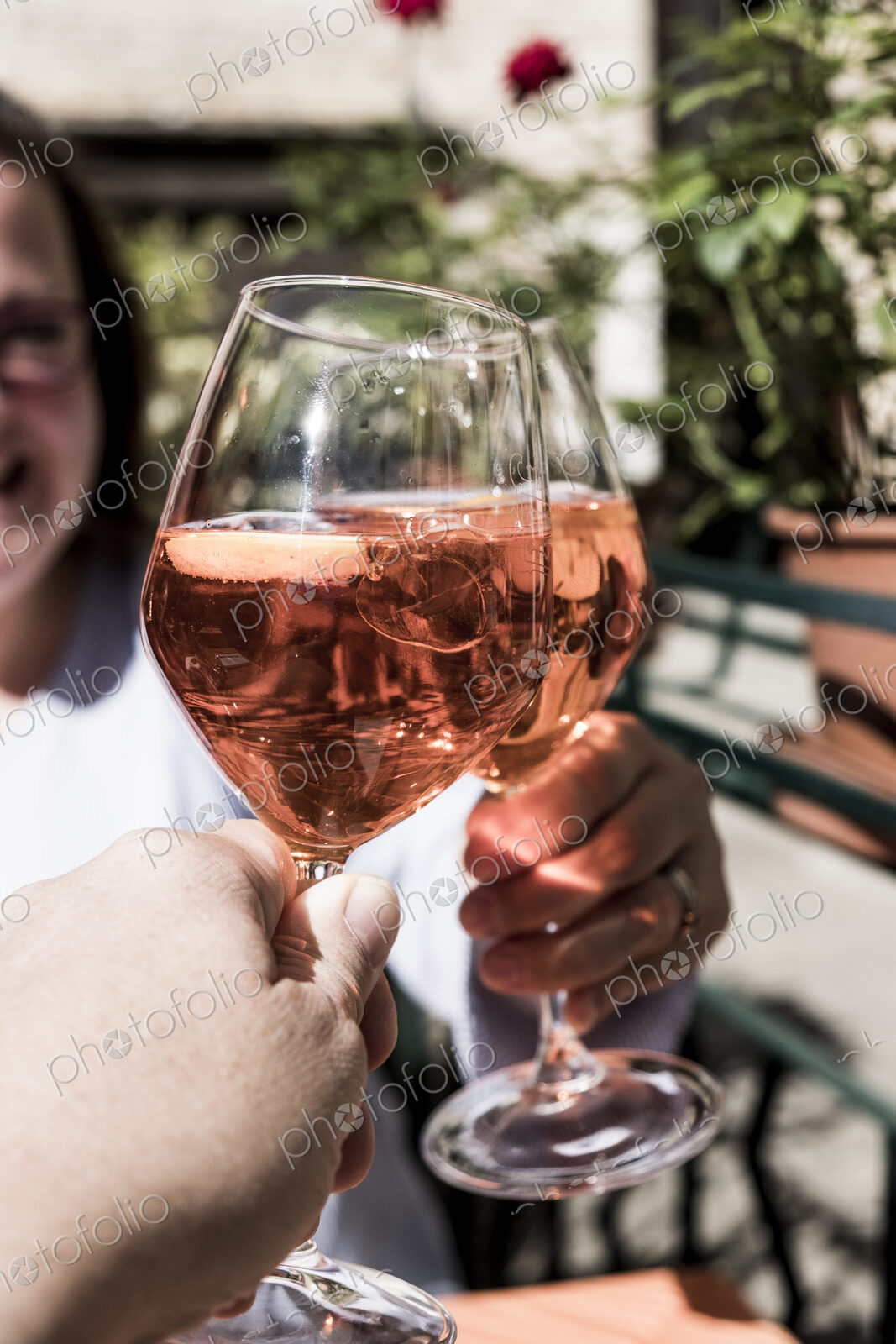 Woman and another person sitting at a table toasting with wine glasses of Aperol Spritz.