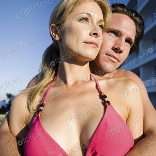 Woman and man in swimwear hugging, enjoying the sunshine.