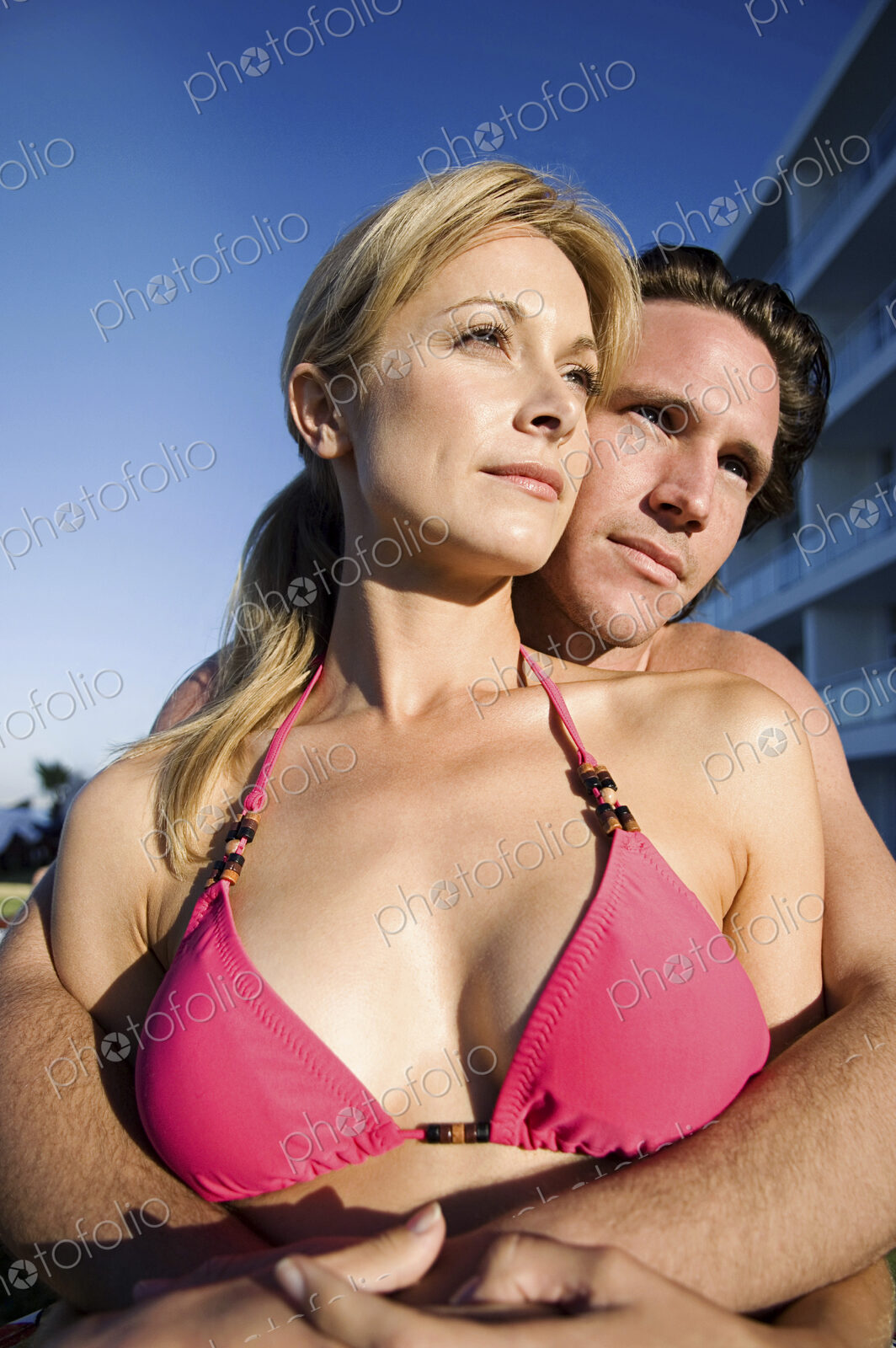 Woman and man in swimwear hugging, enjoying the sunshine.