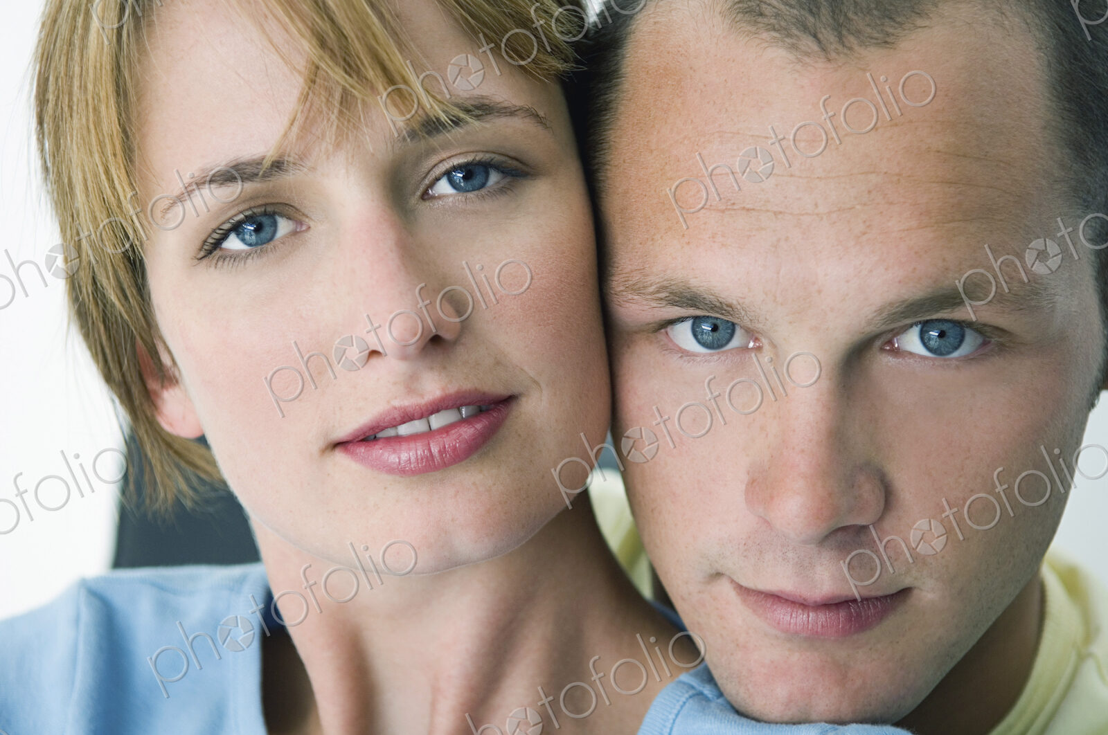 Woman and man smiling at camera with white background.