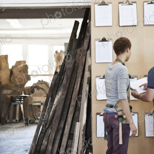 Woman and man team of factory workers checking project inventory in a woodworking factory.