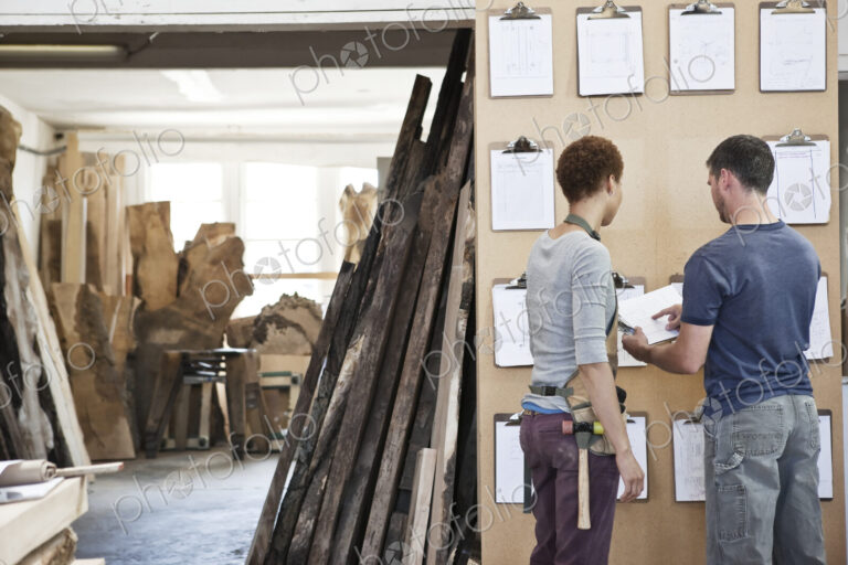 Woman and man team of factory workers checking project inventory in a woodworking factory.