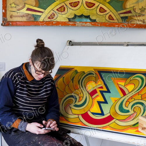 Woman artist sitting by a drawing table checking her mobile phone. Woman artist sitting by a drawing table checking her mobile phone.