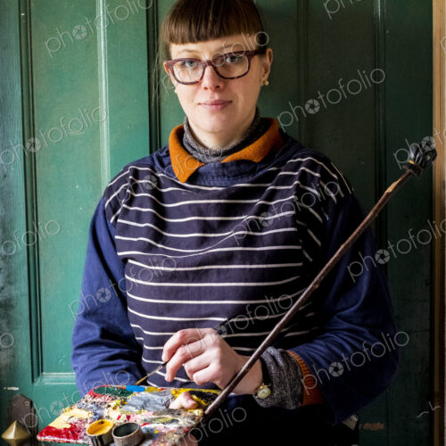 Woman artist wearing glasses holding paintbrush, palette and Mahlstick, looking at camera. Woman artist wearing glasses holding paintbrush, palette and Mahlstick, looking at camera.