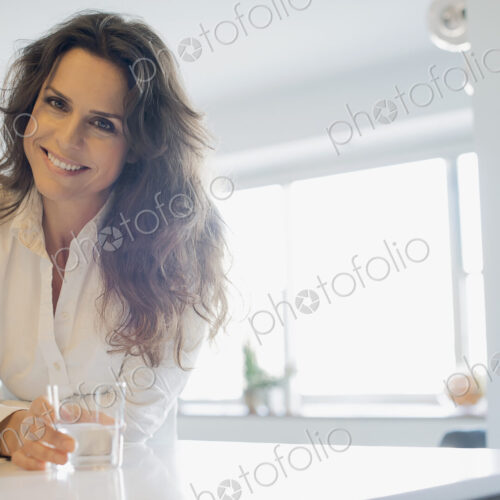 Woman at home in kitchen with glass of water