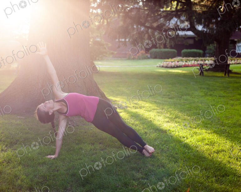 Woman balancing in yoga pose in park.
