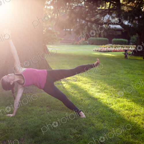 Woman balancing on side in yoga pose in park. Woman balancing on side in yoga pose in park.