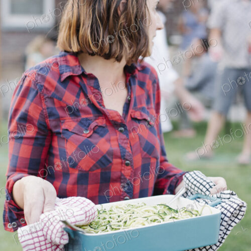 Woman carrying a large dish of vegetables in a garden. Woman carrying a large dish of vegetables in a garden.