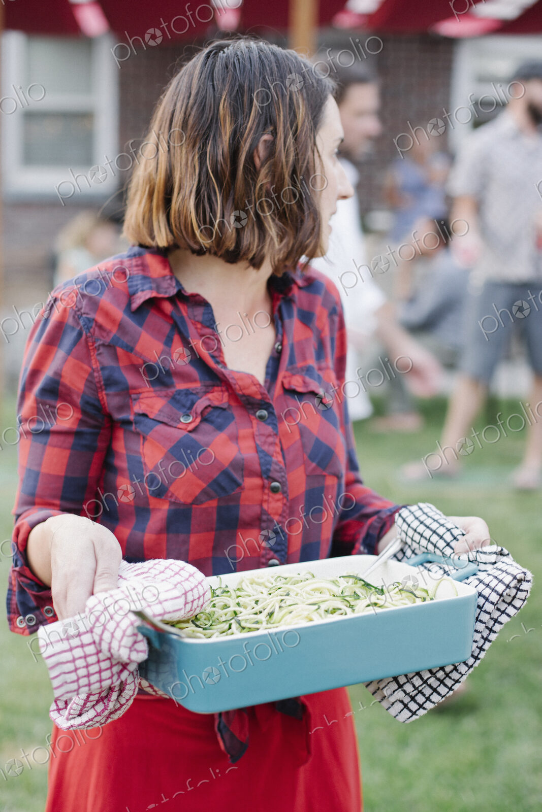 Woman carrying a large dish of vegetables in a garden.