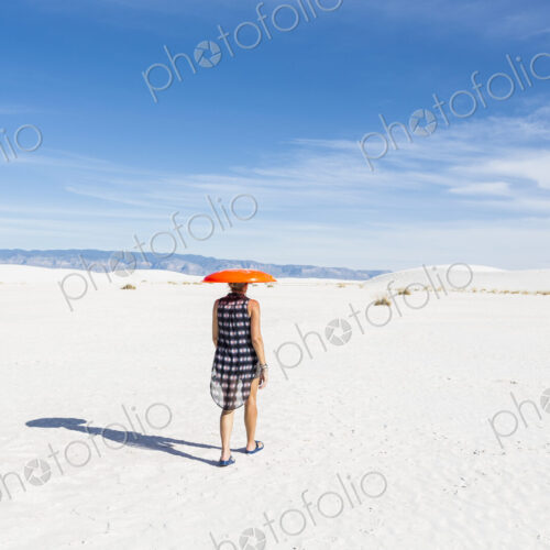 Woman carrying orange sled on her head, White Sands Nat'l Monument, NM