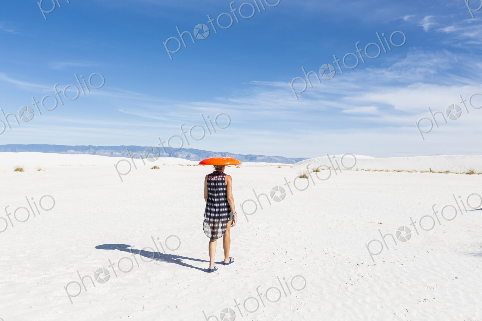 Woman carrying orange sled on her head, White Sands Nat’l Monument, NM