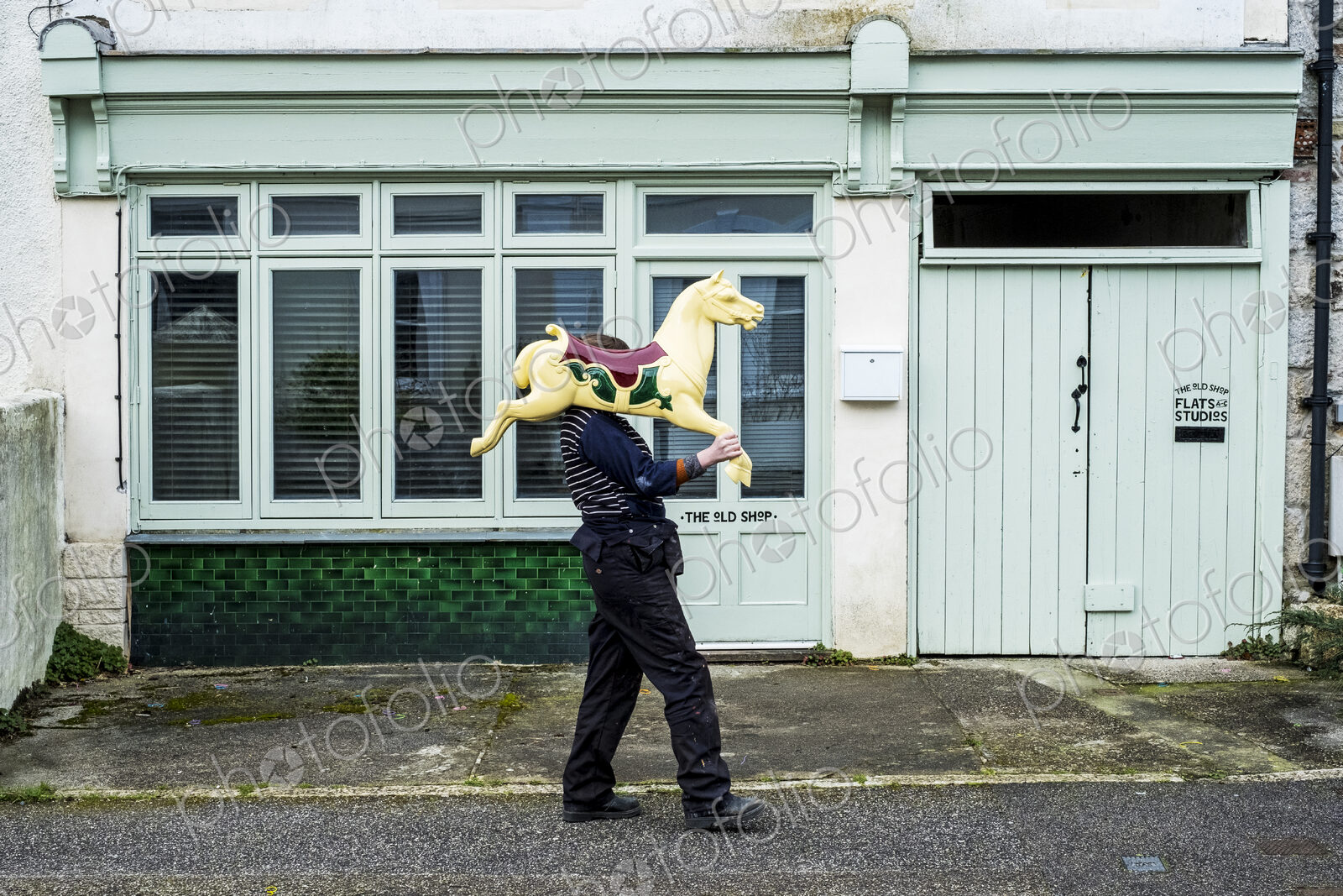 Woman carrying traditional wooden horse from merry-go-round on her shoulder.