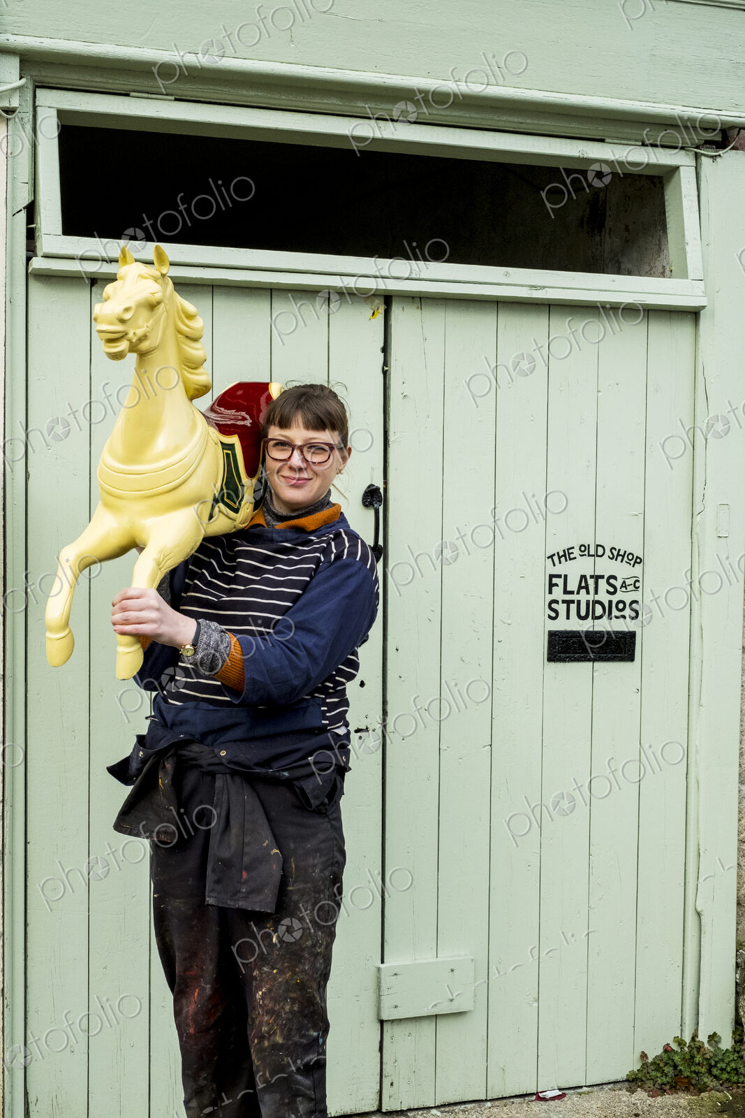 Woman carrying wooden painted carousel galloper horse on her shoulder