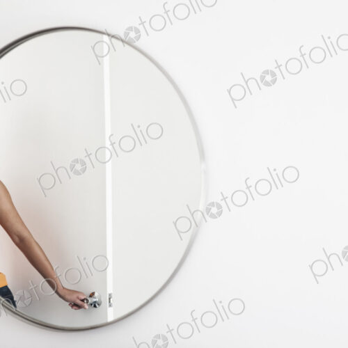 Woman closing a door in a room, reflected in a round mirror. Woman closing a door in a room, reflected in a round mirror.