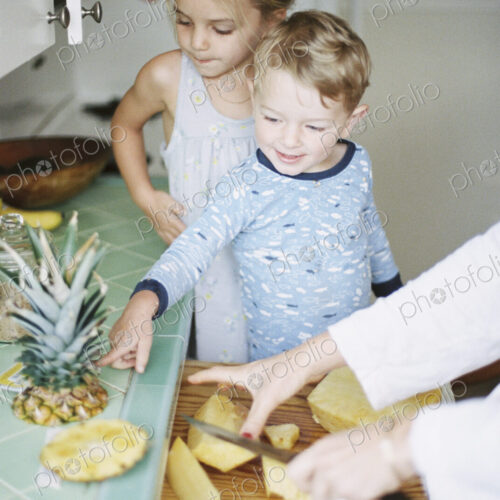Woman cutting a fresh pineapple for her children.