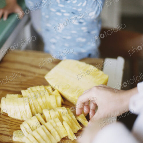 Woman cutting a fresh pineapple for her children.